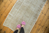 Distressed vintage Turkish Oushak runner with faded ivory, beige, and charcoal medallion.