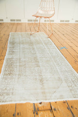 Faded geometric pattern and textured wear on an ivory and beige Oushak runner.