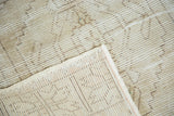Distressed Oushak rug corner, showing worn ivory pile, woven back, and original side selvage.