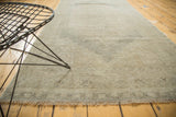 Vintage distressed Oushak runner displaying faded geometric medallions and soft, worn texture in neutral tones.