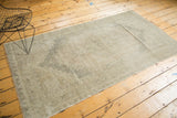 Distressed vintage Oushak runner's corner, showing worn geometric patterns, fringe, and blanket stitched side.