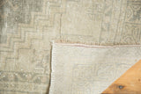 Distressed Oushak rug runner corner, showing geometric pile, hand-knotted foundation, and blanket-stitched fringe.