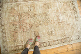 Worn distressed Oushak rug, showing pictorial imagery, faded ivory, dusty rose, and brown.