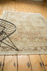 Decorative distressed Oushak rug showing worn ivory pile, faint pictorial motifs, and fringe.