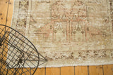 Corner of distressed Oushak rug, showing worn texture, exposed foundation, and ivory fringe.