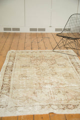 Distressed Oushak rug corner showcasing pictorial buildings, secure fringe, worn ivory and blush tones.