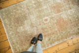 Distressed vintage Oushak runner showing faded blush, beige, and charcoal geometric patterns.