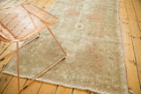 Distressed vintage Oushak runner showing faded geometric designs, worn pile, and soft fringe.