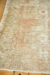 Distressed Oushak rug corner, showing geometric pattern, subtle colors, and fringe.
