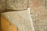 Folded corner of distressed Oushak rug, showing hand knotted foundation and faded pile.