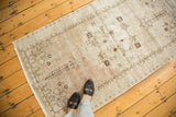 Distressed vintage Oushak runner showing faded blush, beige, and chocolate brown stylized motifs.