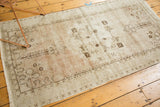 Distressed vintage Oushak runner edge, with pale blush, beige, and brown graphic border.