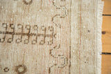 Textured pile of a distressed Oushak rug, showing mostly even wear in beige and brown.