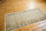 Distressed vintage Oushak runner showing faded beige and brown geometric medallions and floral borders.