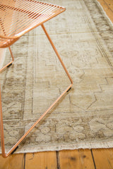 Distressed vintage Oushak runner with faded pale beige, charcoal brown geometric motifs, and visible fringe.