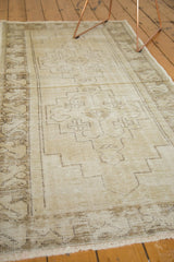 Distressed Oushak runner's faded beige pile, geometric pattern, and fringe detail.