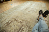 Distressed Oushak runner, faded beige and chocolate geometric medallion with visible worn pile.