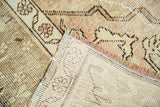 Hand-knotted vintage Oushak rug back and distressed pile in beige, mauve, showing wear.