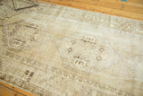 Fringed end of distressed Oushak rug, showing wear and chocolate brown quatrefoil pattern.
