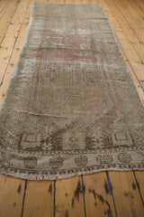 Textured fringe and worn geometric motifs on the end of a distressed Oushak runner.