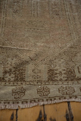 Distressed Oushak rug end, with geometric border, worn pile texture, and fringe.