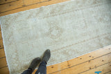 Distressed Oushak runner showing worn ivory pile and faded rectilinear motifs.