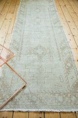 Distressed Oushak rug runner's ivory fringe, rectilinear pattern, and visible small paint blemish.