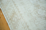 Distressed vintage Oushak rug, ivory pile, faded rectilinear pattern, side selvage, and blemish.