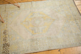 Distressed Oushak rug with faded saffron yellow motifs, slate blue border, and noticeable abrash.