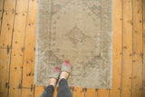 Distressed Oushak rug with muted beige, blush, green tones and faded floral medallion.