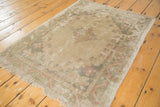 Distressed Oushak rug texture with low pile, foundation showing, and faded beige floral scrolls.