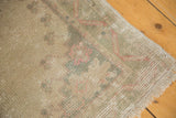Distressed low pile with faded pink and green flower scrolls on a vintage Oushak rug fringe.