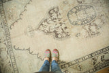 Pale beige field and faded charcoal medallion on a distressed vintage Oushak rug.