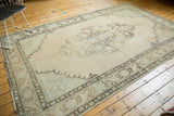 Faded charcoal patterns on pale beige field in a distressed Oushak rug corner.