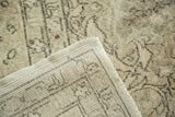 Vintage distressed Oushak rug corner showing pale pile and hand-knotted foundation.