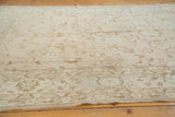 Low pile distressed vintage Oushak rug with pale beige blush and brown floral motifs.