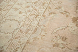 Faded pale beige and blush lotus motifs with even distress on a vintage Oushak rug.