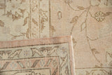 Folded corner of distressed Oushak rug, showing pile wear and hand-knotted foundation.