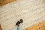 Distressed Oushak runner, repeating zig-zag chevron pattern, faded ivory, blush, and bronze.