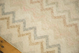 Distressed ivory Oushak runner with zig-zag pattern in blush, bronze, and faded blue.