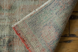 Distressed vintage Oushak carpet pile with coral-stitched edge and hand-knotted woven foundation.