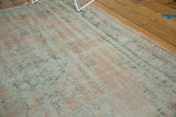 Distressed Oushak rug edge, showing blush and ivory worn pile with visible foundation.