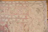 Corner detail of a distressed Oushak showing worn pile, exposed foundation, and faded red florals.