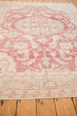 Low pile and even wear across the faded red and ivory distressed Oushak carpet.