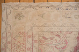 Detailed corner view of a distressed Oushak rug highlighting its low pile and faded vinery.