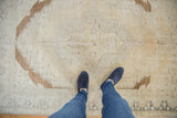 Distressed Oushak rug displaying faded beige tones and brown bronze geometric motifs.