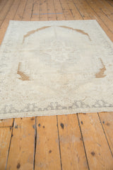 Cream vintage Oushak rug corner with distressed texture and subtle gray border.