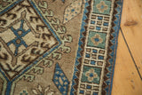 Vintage Serab rug close-up showing sea foam green floral border, navy blue and brown hook-and-latch motif.