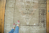 Distressed vintage Oushak rug with faded beige abrashes, geometric corner, and checkered border.