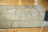 Distressed Oushak carpet corner, showing faded geometric patterns and textural pile in pale beige.